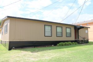 Beige modular home on grassy lawn.